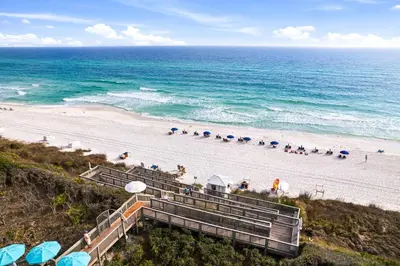 a beach with stairs and umbrellas and the ocean at HP 21W Gulf Front Condo by 30A Escapes in Rosemary Beach