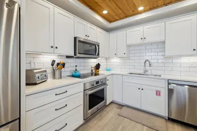 a kitchen with white cabinets and stainless steel appliances at HP 21W Gulf Front Condo by 30A Escapes in Rosemary Beach