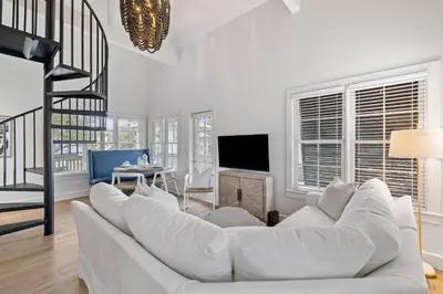 a living room with a white couch and a tv at Stairway to Heaven Carriage by 30A Escapes in Rosemary Beach