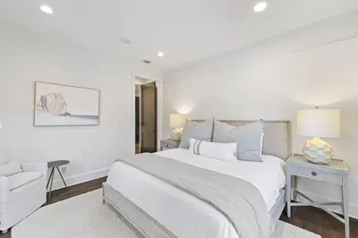 a white bedroom with a large bed and a chair at Stairway to Heaven Cottage by 30A Escapes in Rosemary Beach