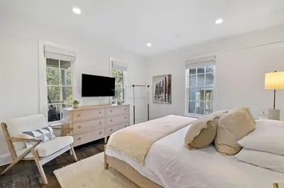 a white bedroom with a bed and a tv at Stairway to Heaven Cottage by 30A Escapes in Rosemary Beach