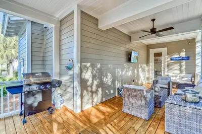 a screened in porch with a grill on a deck at 100 Lifeguard Loop East by 30A Escapes in Rosemary Beach