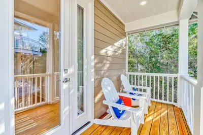 a porch with two rocking chairs and a door at 100 Lifeguard Loop East by 30A Escapes in Rosemary Beach