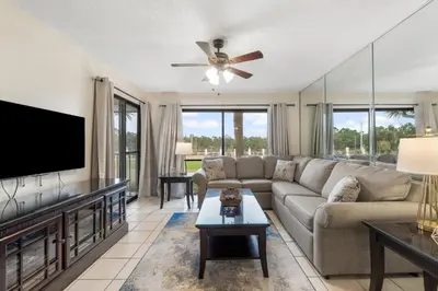 a living room with a couch and a flat screen tv at Edgewater Golf Villas #1714 by InJoy Vacations in Panama City Beach