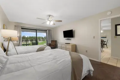 a bedroom with two beds and a flat screen tv at Edgewater Golf Villas #1714 by InJoy Vacations in Panama City Beach