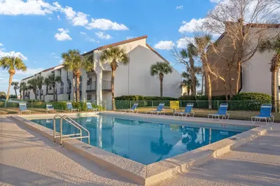 a swimming pool with chairs and a building at Edgewater Golf Villas #1714 by InJoy Vacations in Panama City Beach