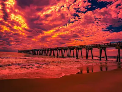 a pier on the beach under a cloudy sky at Edgewater Golf Villas #1714 by InJoy Vacations in Panama City Beach