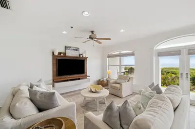 a living room with white furniture and a flat screen tv at Sunset Beach 102C by 30A Escapes in Rosemary Beach
