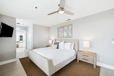 a white bedroom with a bed and a tv at Sunset Beach 102C by 30A Escapes in Rosemary Beach