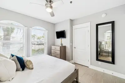 a bedroom with a white bed and a mirror at Sunset Beach 102C by 30A Escapes in Rosemary Beach