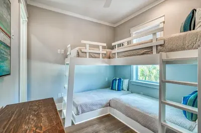 a bedroom with two bunk beds and a table at Sanity By the Sea by 30A Escapes in Inlet Beach