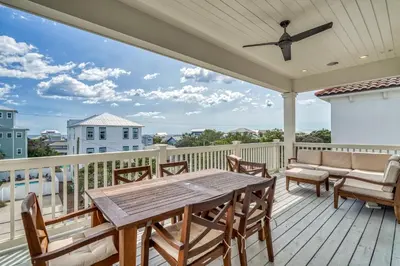 a porch with a wooden table and chairs at Sanity By the Sea by 30A Escapes in Inlet Beach