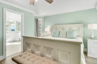 a bedroom with a king sized bed with blue pillows at Searenity Now by 30A Escapes in Seagrove Beach