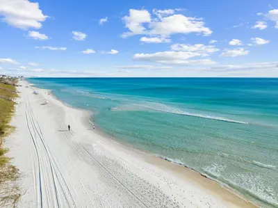 a beach with people walking on the sand and the ocean at Kaiya Beach Resort in Inlet Beach