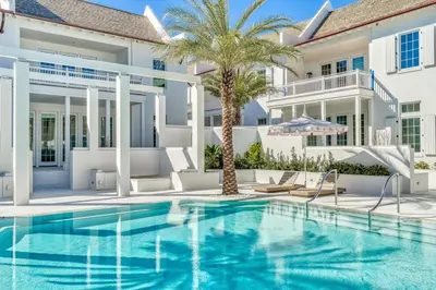 a swimming pool in front of a house with a palm tree at Kaiya Beach Resort in Inlet Beach