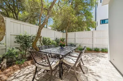 a patio with a table and chairs and a fence at Dune Our Thing by 30A Escapes in Inlet Beach