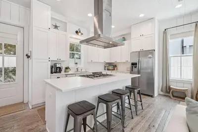 a kitchen with white cabinets and a island with bar stools at Dune Our Thing by 30A Escapes in Inlet Beach