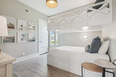 a white bedroom with a bed and a table at Dune Our Thing by 30A Escapes in Inlet Beach