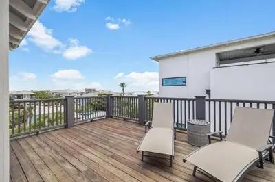 a balcony with two chairs and a white building at Dune Our Thing by 30A Escapes in Inlet Beach