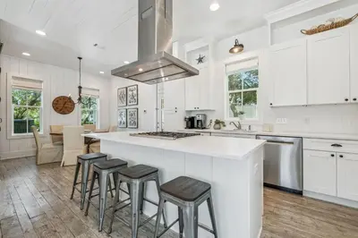a kitchen with white cabinets and a island with bar stools at Dune Our Thing by 30A Escapes in Inlet Beach
