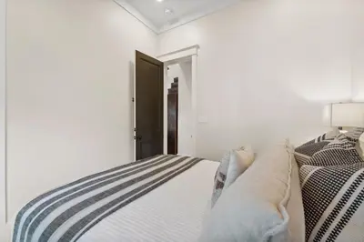 a white bedroom with a bed and a black door at Pappas Carriage by 30A Escapes in Rosemary Beach