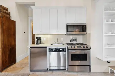 a kitchen with stainless steel appliances and white cabinets at Pappas Carriage by 30A Escapes in Rosemary Beach