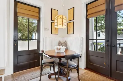 a dining room with black doors and a table and chairs at Pappas Carriage by 30A Escapes in Rosemary Beach