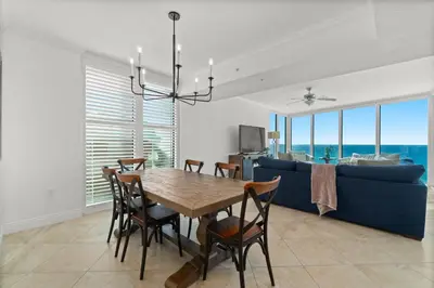 a dining room with a table and a blue couch at Palazzo Unit 301 by 30A Escapes in Panama City Beach