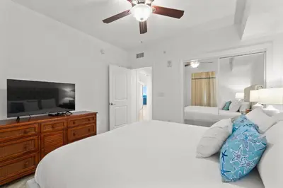a white bedroom with a bed and a ceiling fan at Palazzo Unit 301 by 30A Escapes in Panama City Beach