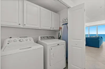 a kitchen with white cabinets and a washer and dryer at Palazzo Unit 301 by 30A Escapes in Panama City Beach