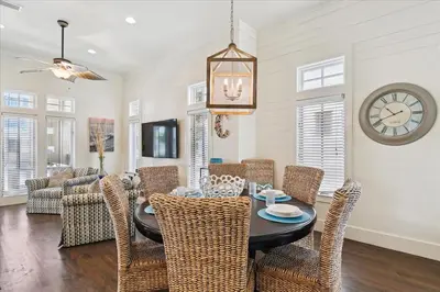 a dining room with a table and chairs and a clock at Summer Cottage by 30A Escapes in Rosemary Beach