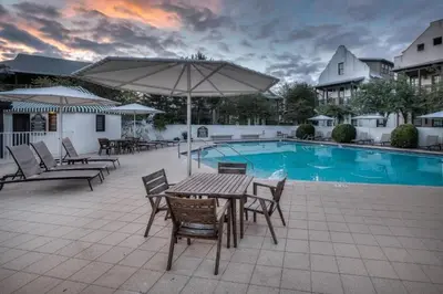 a patio with a table and chairs next to a pool at Summer Cottage by 30A Escapes in Rosemary Beach