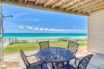 a table and chairs on a patio with a view of the ocean at Mermaid Cove by 30A Escapes in Seacrest