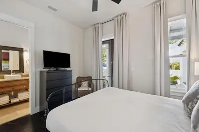 a white bedroom with a bed and a television at Somerset Cottage by 30A Escapes in Rosemary Beach