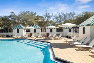 a swimming pool with lounge chairs and umbrellas at Somerset Cottage by 30A Escapes in Rosemary Beach