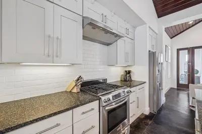 a kitchen with white cabinets and a stove top oven at Somerset Cottage by 30A Escapes in Rosemary Beach