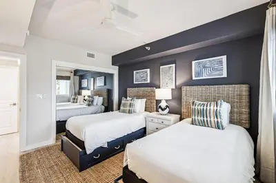 a bedroom with two beds and a blue accent wall at Tranquillity on 30A Unit# 210 by 30A Escapes in Seacrest