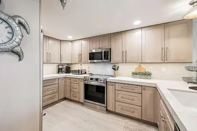 a kitchen with wooden cabinets and a clock on the wall at Tranquillity on 30A Unit# 210 by 30A Escapes in Seacrest