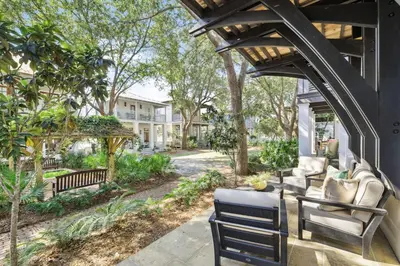 a patio with two chairs and a porch with trees at 21 Hamilton Lane by 30A Escapes in Rosemary Beach