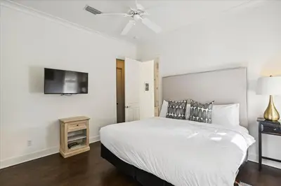 a bedroom with a white bed and a flat screen tv at Casita By The Sea by 30A Escapes in Rosemary Beach