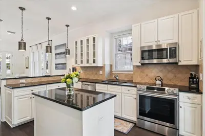 a kitchen with white cabinets and a black counter top at Casita By The Sea by 30A Escapes in Rosemary Beach
