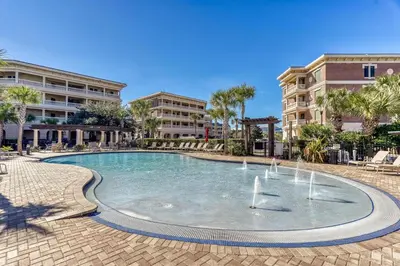 a swimming pool with a fountain in front of some buildings at Sail Away by 30A Escapes in Rosemary Beach