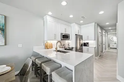 a kitchen with white cabinets and a large island with bar stools at Beachfront Bliss On 30A by 30A Escapes in Seacrest