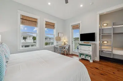 a bedroom with a bed and a tv and windows at Aqua Waters by 30A Escapes in Rosemary Beach