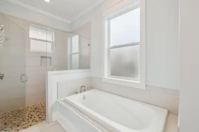 a white bathroom with a tub and a window at Aqua Waters by 30A Escapes in Rosemary Beach