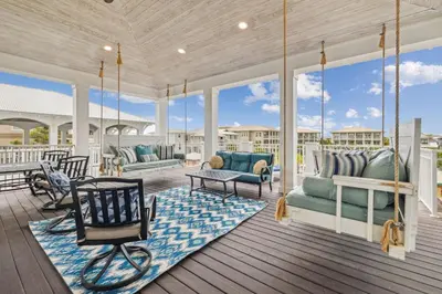 a porch with a swing and chairs on a deck at Aqua Waters by 30A Escapes in Rosemary Beach