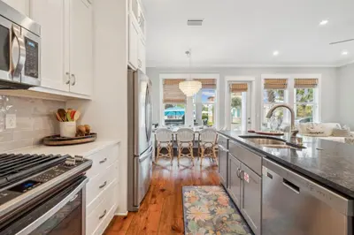 a kitchen with white cabinets and stainless steel appliances at Aqua Waters by 30A Escapes in Rosemary Beach