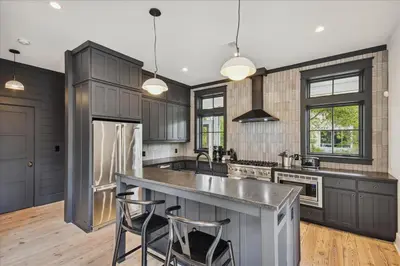 a kitchen with gray cabinets and a island with bar stools at HollieBird House by 30A Escapes in Watersound Beach