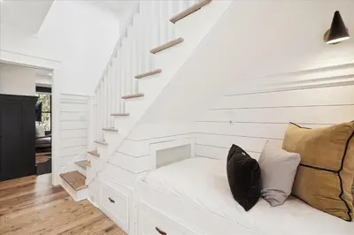 a white room with a white bench under the stairs at HollieBird House by 30A Escapes in Watersound Beach