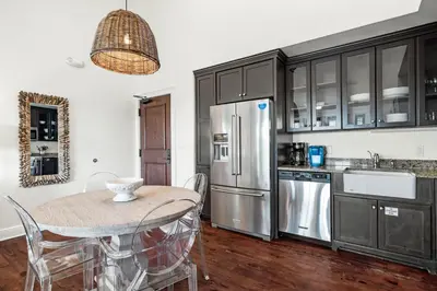 a kitchen with a table and a stainless steel refrigerator at Rosemary Thyme by 30A Escapes in Rosemary Beach